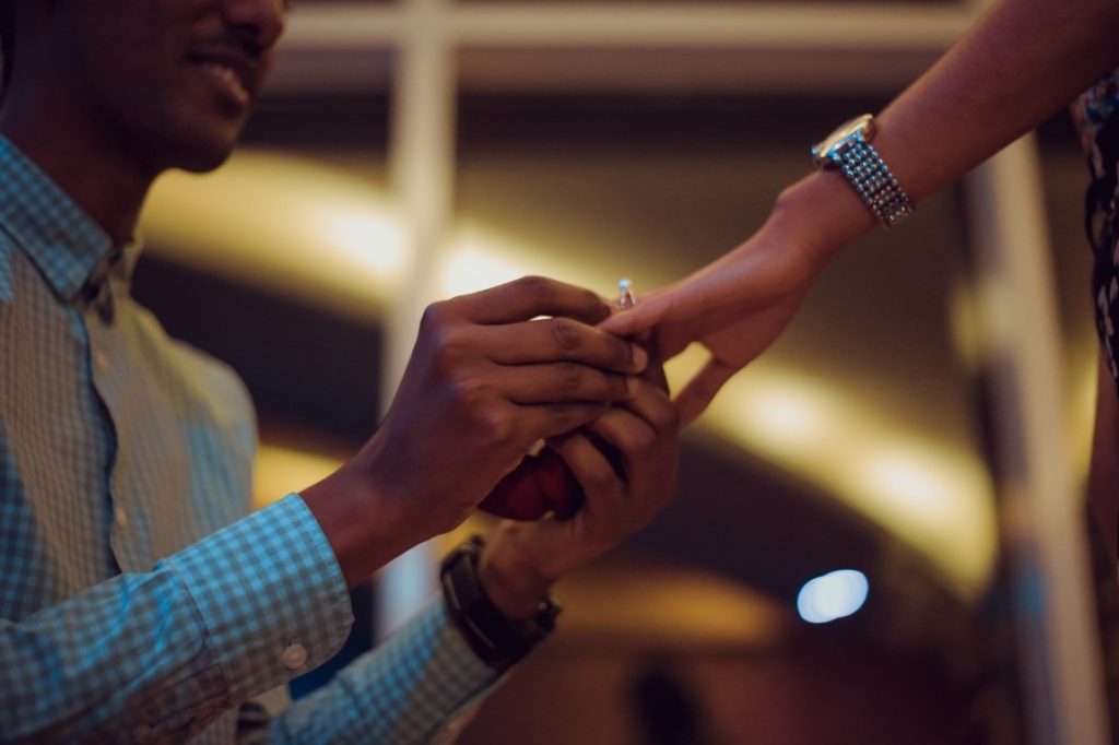 man putting on a ring on his fiancee's finger