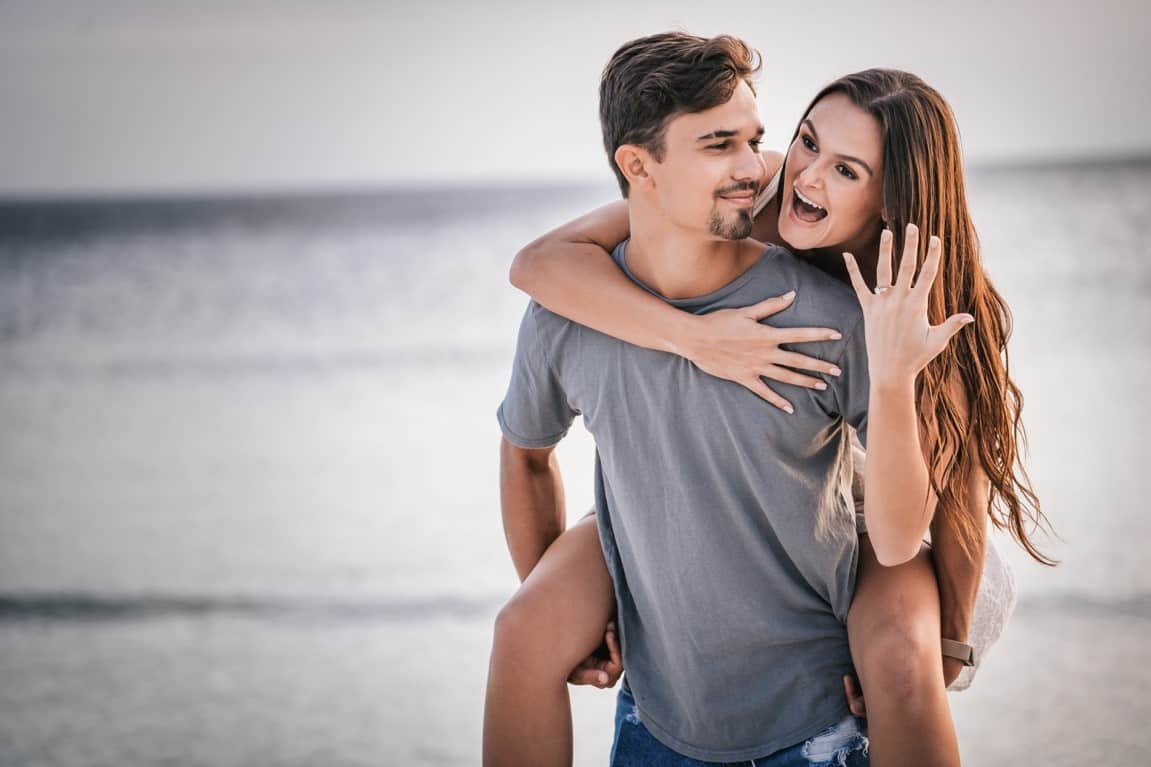 woman showing off her ring while piggyback riding with her man