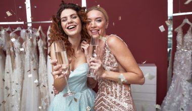 two maid of honor laughing and holding white wine