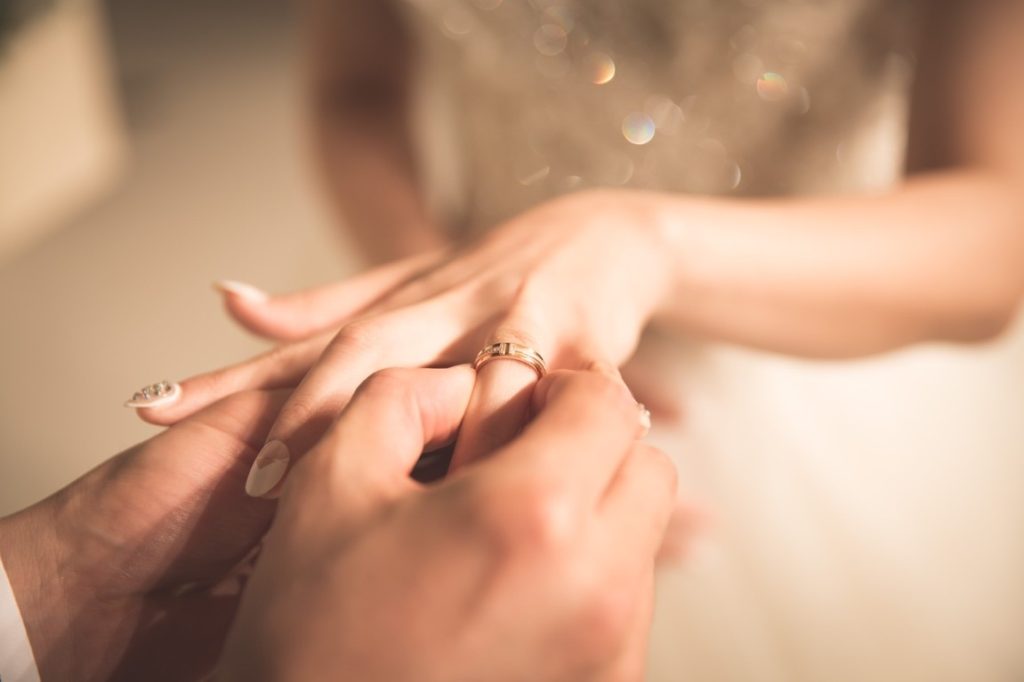 groom putting on bride's wedding ring