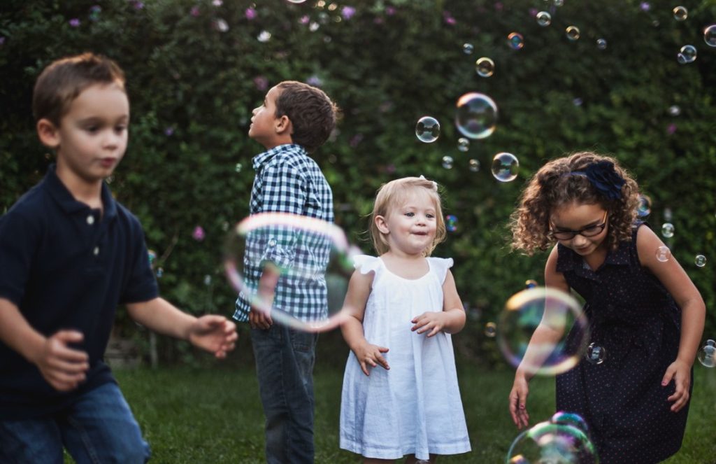 kids blowing bubbles in a park