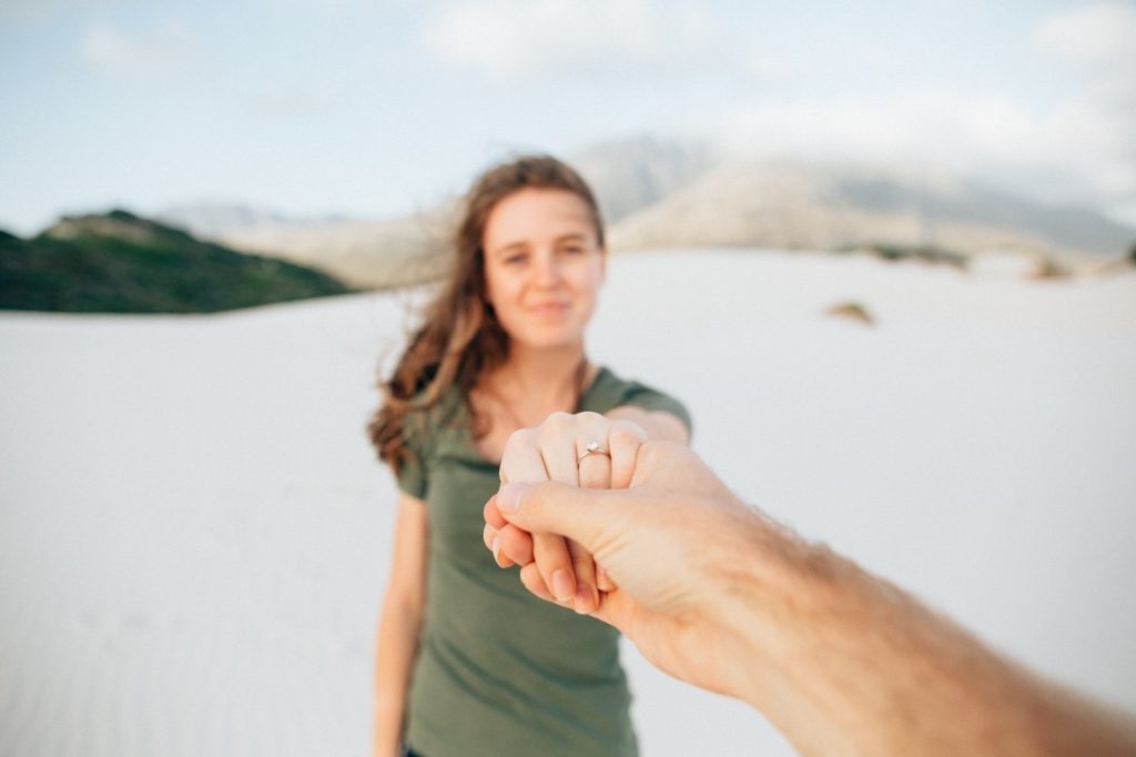 man holding hand with a woman showing off engagement ring
