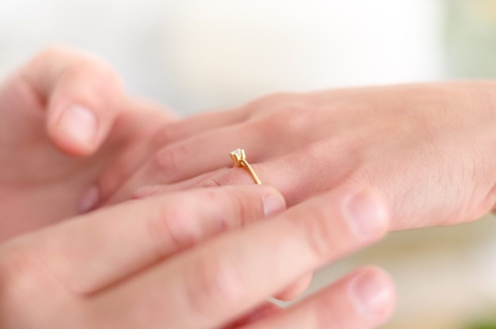 man putting on a ring on a woman's hand