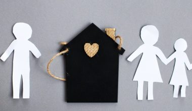 Paper chain cut family near toy house on gray background. Divorce and broken family concept