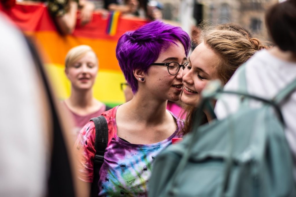 woman kissing girlfriend on the cheeks