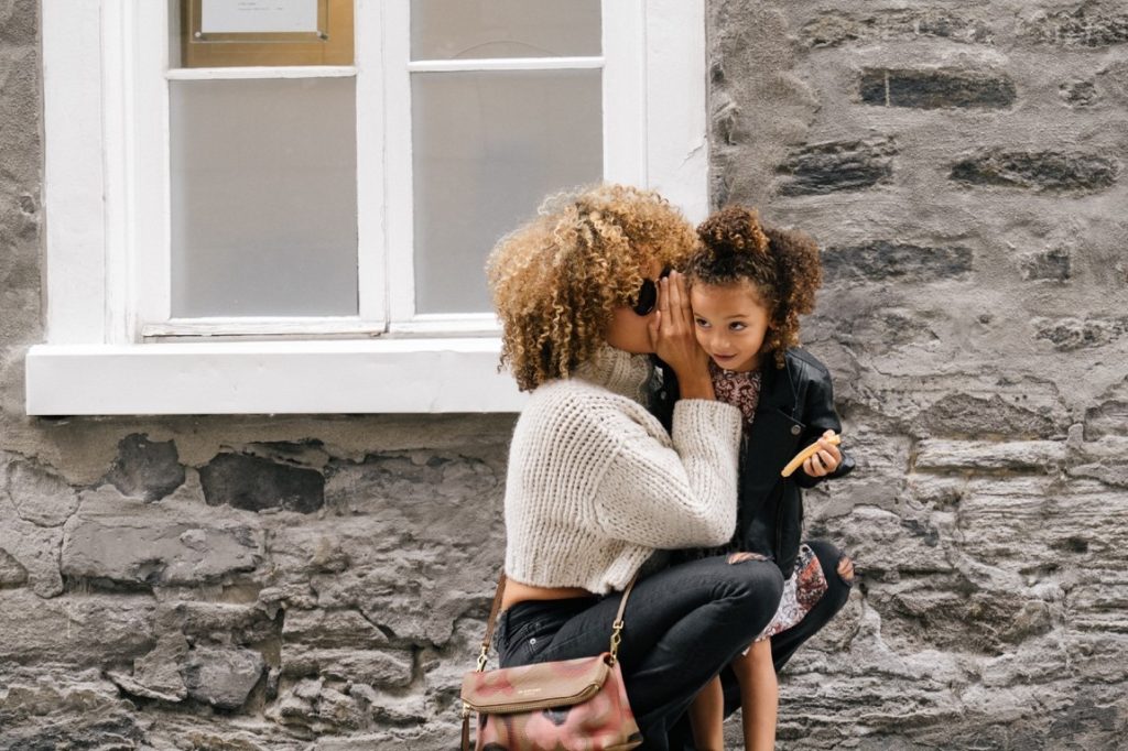 woman whispering on a little girl's ear