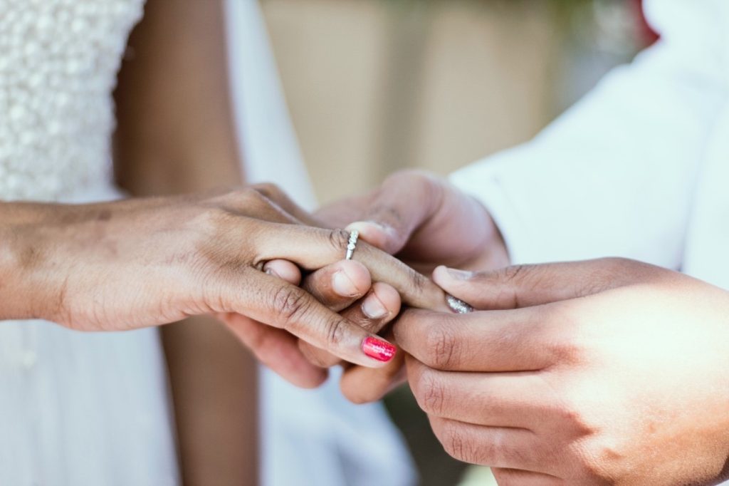 man putting on a ring on bride