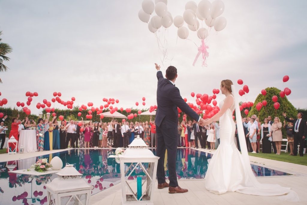 newlyweds and guests throwing balloons up in the sky