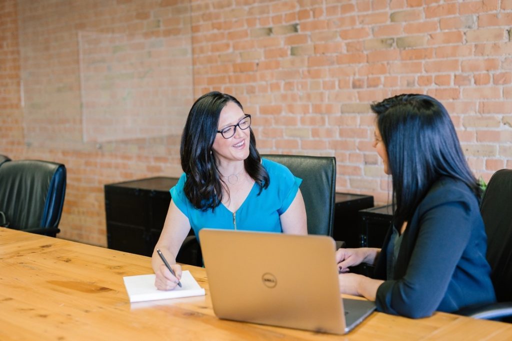 two woman talking at boardroom