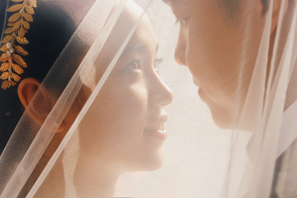 man and woman looking at each other underneath a veil