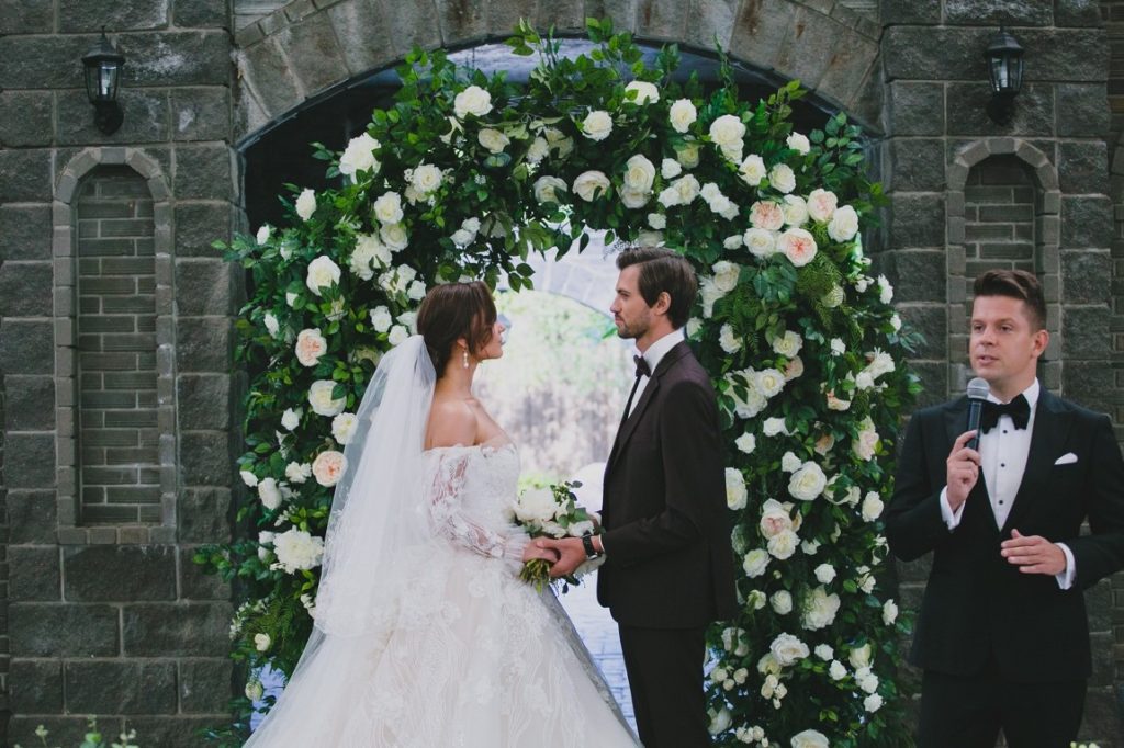 newlyweds looking at each other while a man is speaking