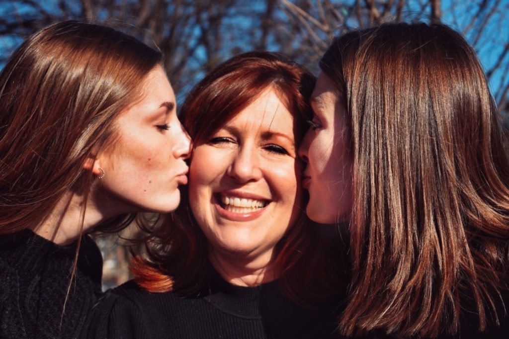 two girls kissing their mom