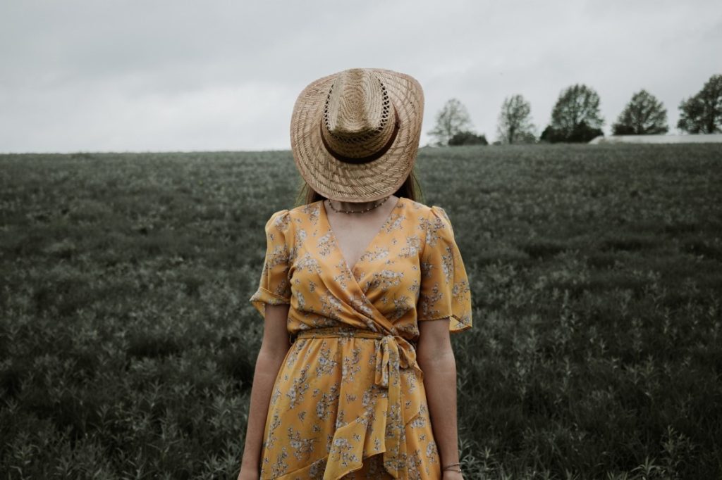 woman covering her face with boater hat