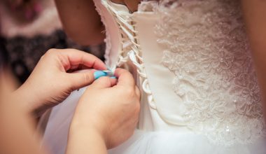 woman tying up bride's wedding dress