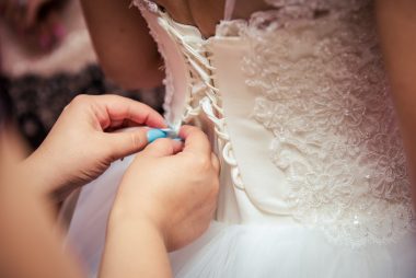 woman tying up bride's wedding dress