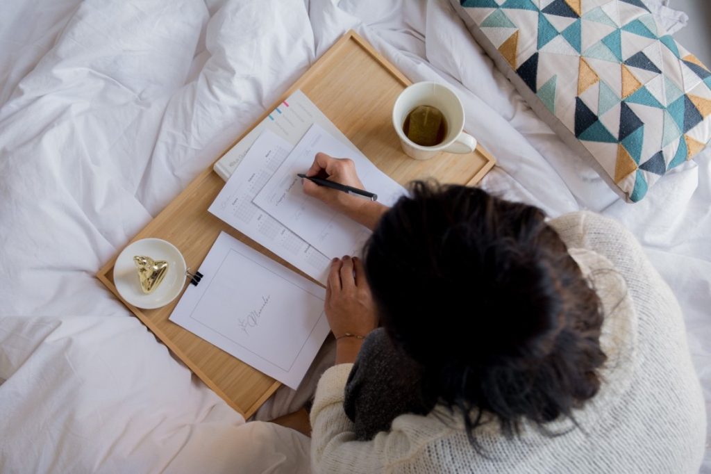 woman writing on her bed