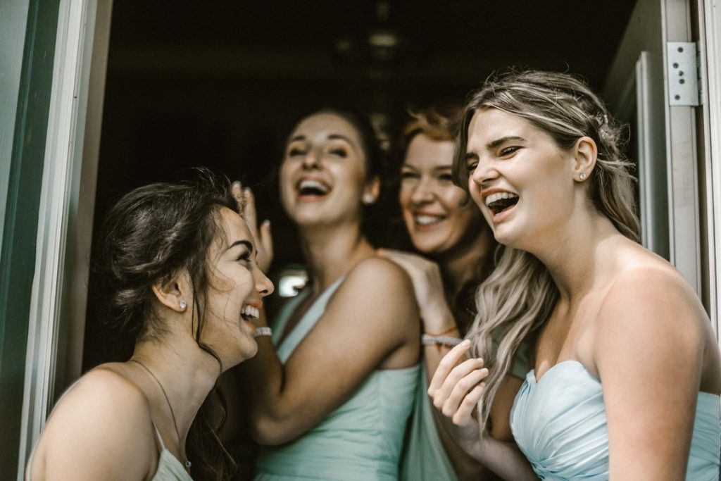 bride and her bridesmaids at the door laughing