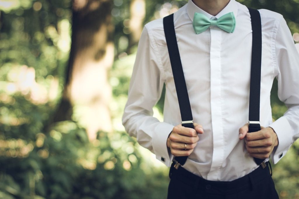 man wearing suspenders and green bow