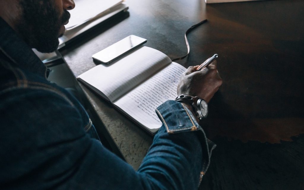 man writing on his notebook