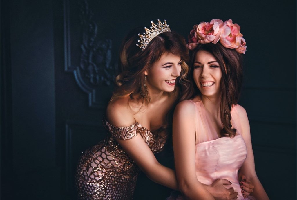 two girls laughing and wearing a crown