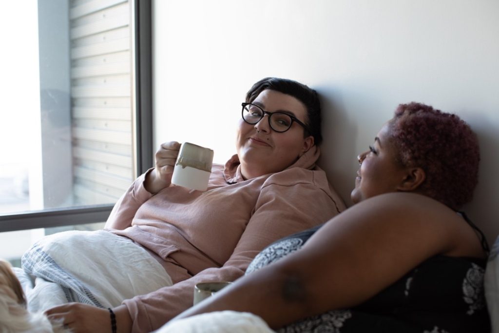 two woman talking bed