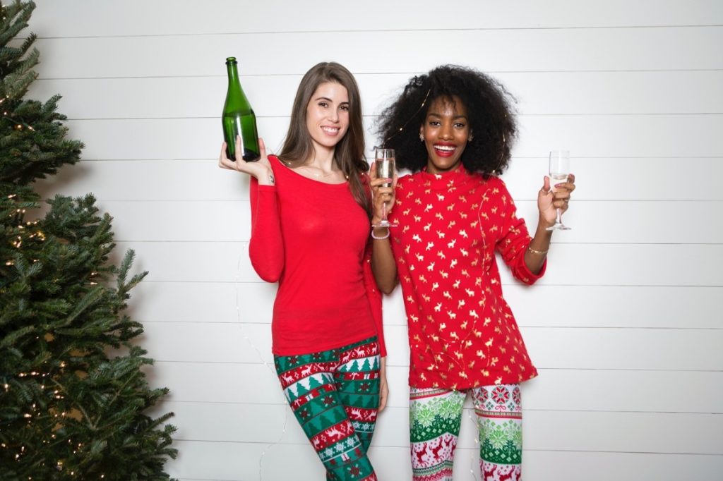 two woman wearing christmas clothes and drinking wine