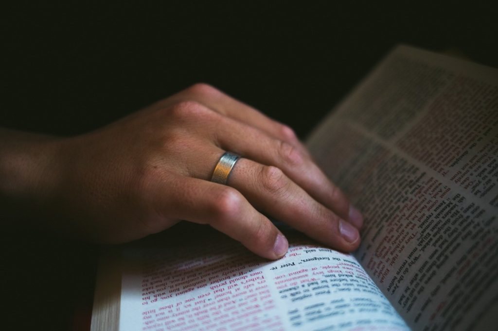 woman's hand with ring and bible