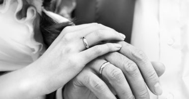 hands of bride and groom wearing wedding band