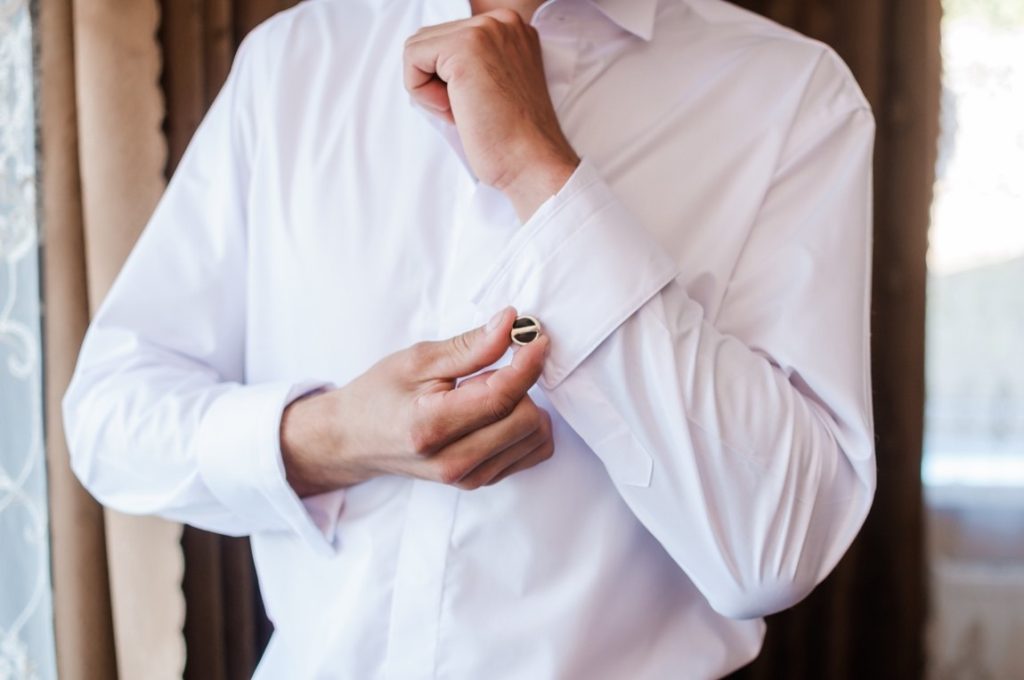 man holding his cufflinks