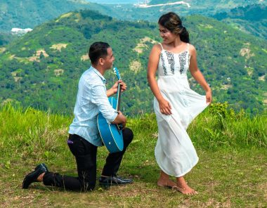 man kneeling serenading a woman