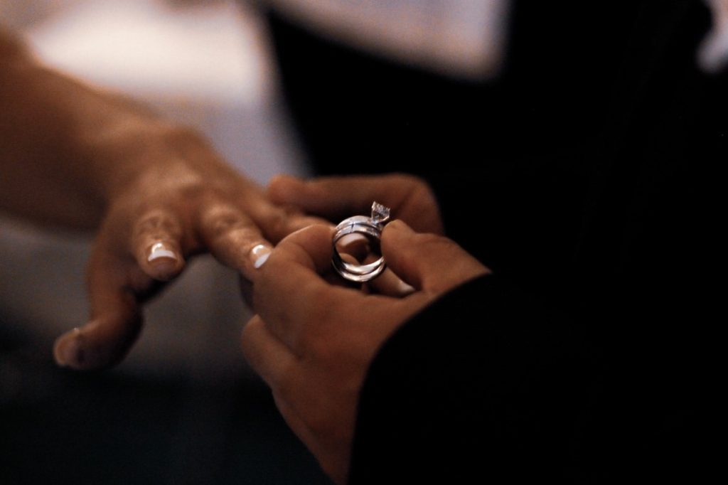 man putting on wedding band on bride