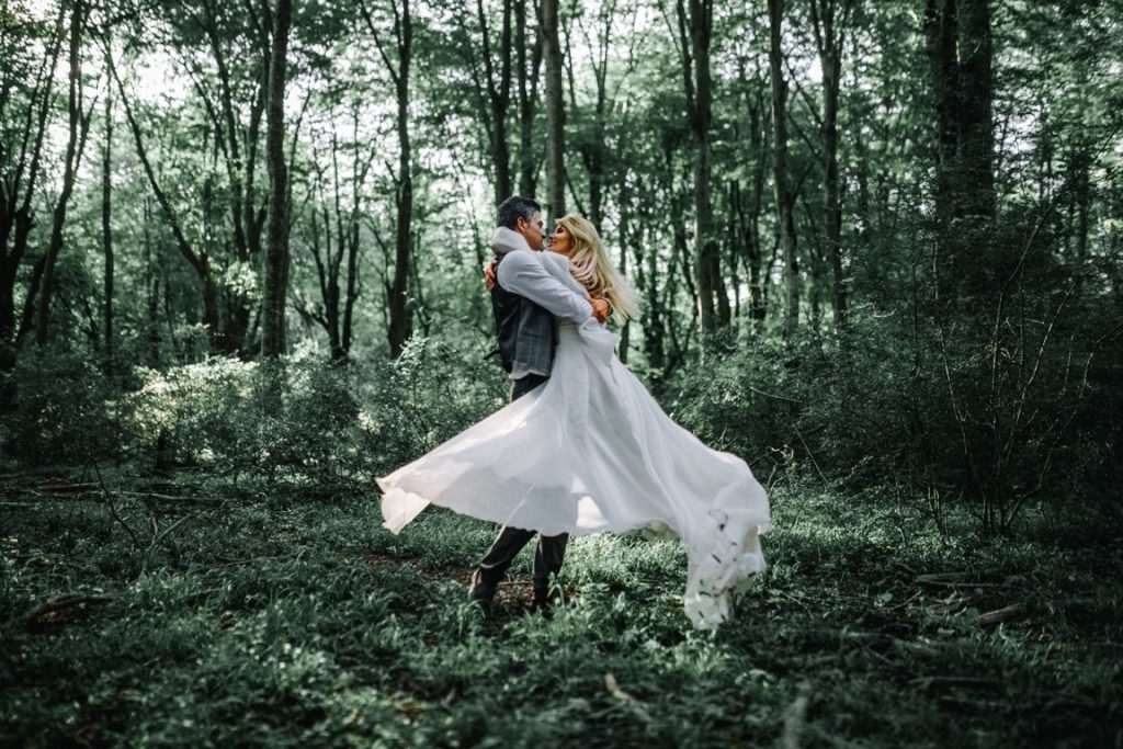 groom carrying the bride in the middle of a forest