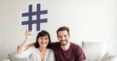 man and woman holding a hashtag sign