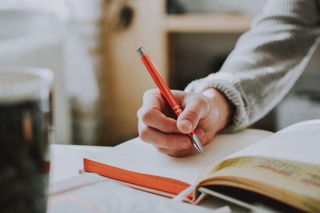 man writing on a notebook