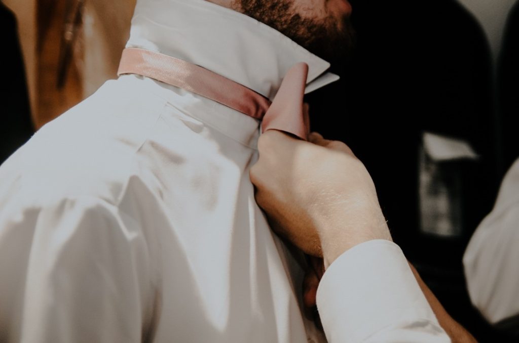 person's hand fixing a man's tie