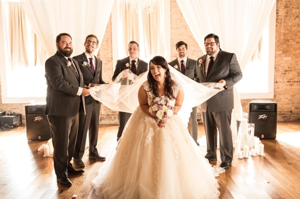 groomsmen holding bride's veil