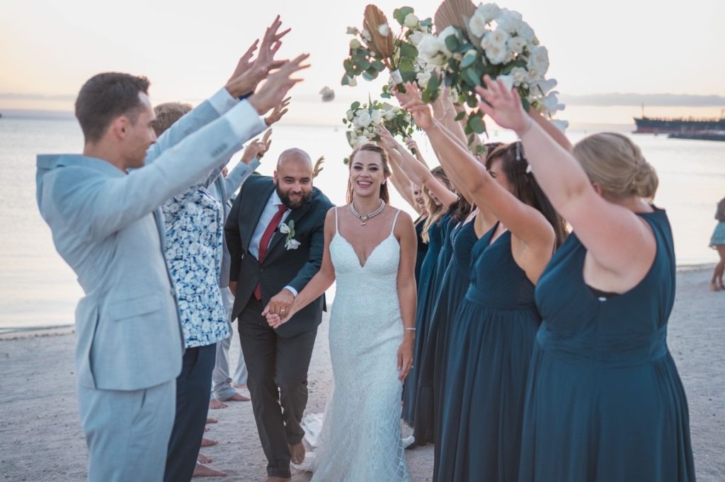 newlyweds walking through their groomsmen and bridesmaids