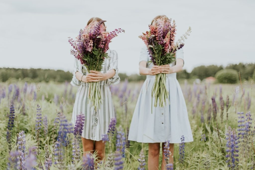two woman holding a bouquet of wildflowers