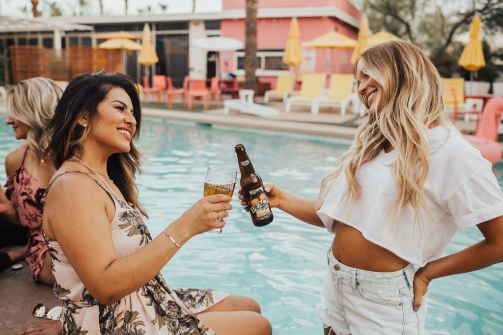 two women clinking beers