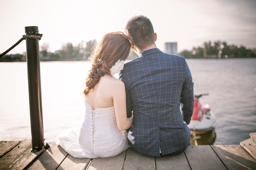 bride and groom sitting on a dock