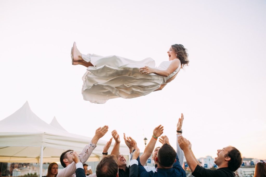 groomsmen throwing bride up the air