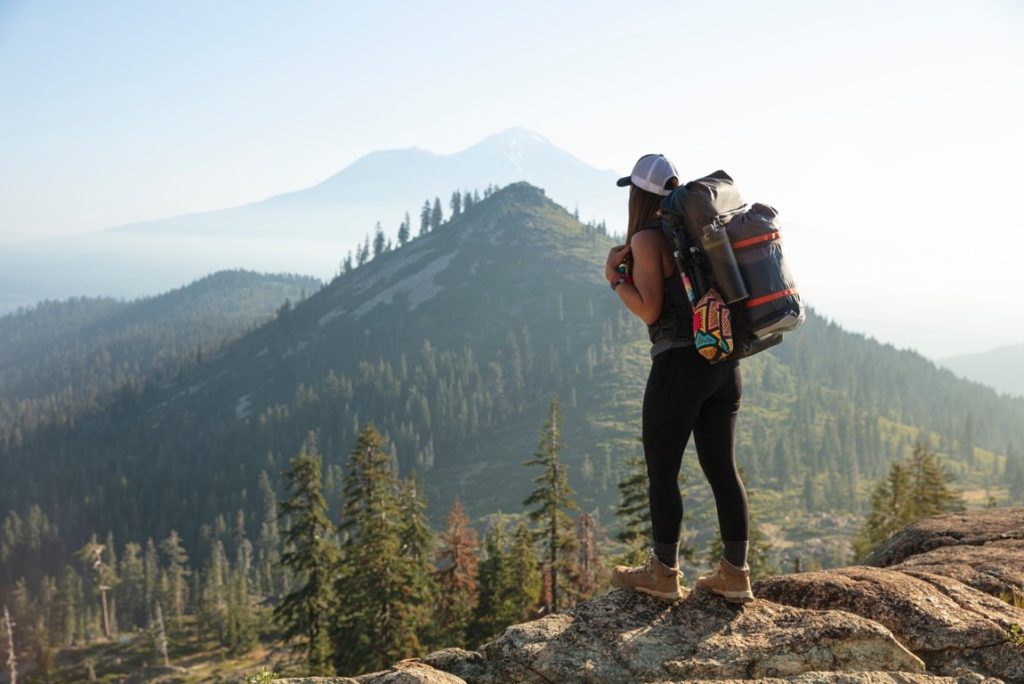 woman standing near a cliff with a backpack