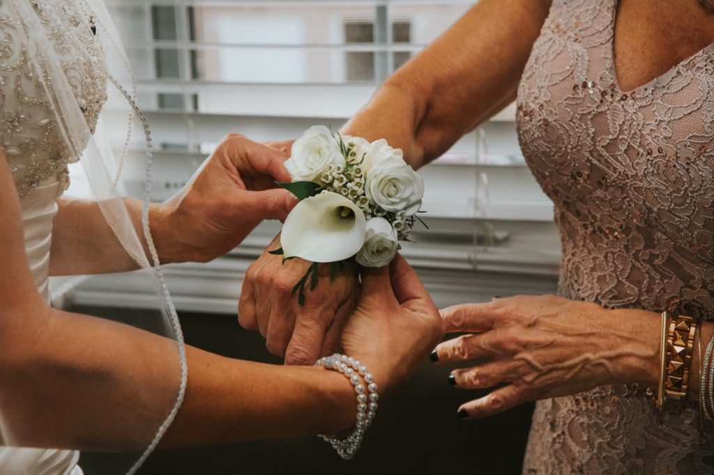 bride putting corsage on her mother's wrist