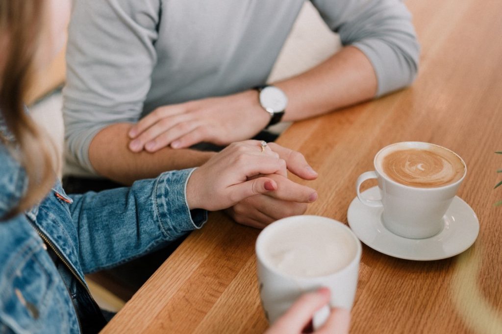 man and woman holding hands on a coffee shop
