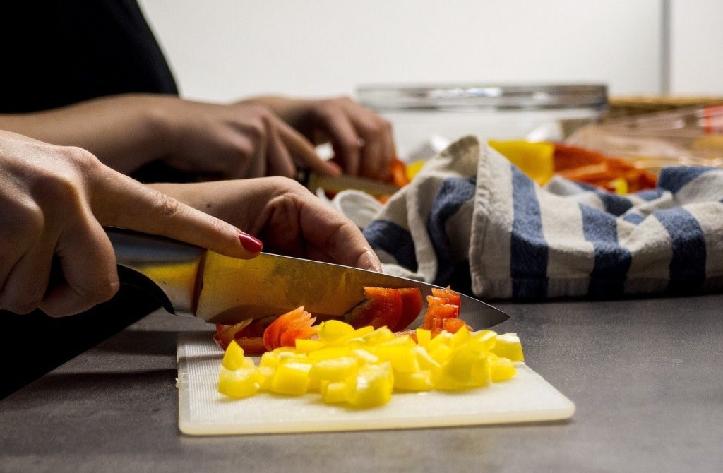 two people chopping tomatoes