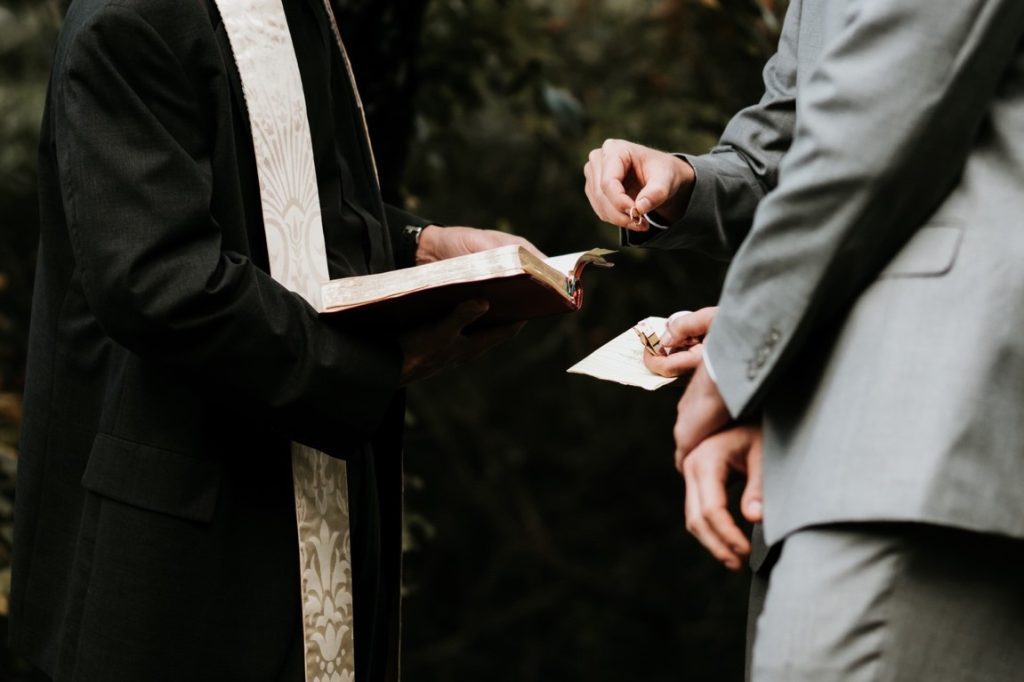 best man giving wedding rings to newlyweds