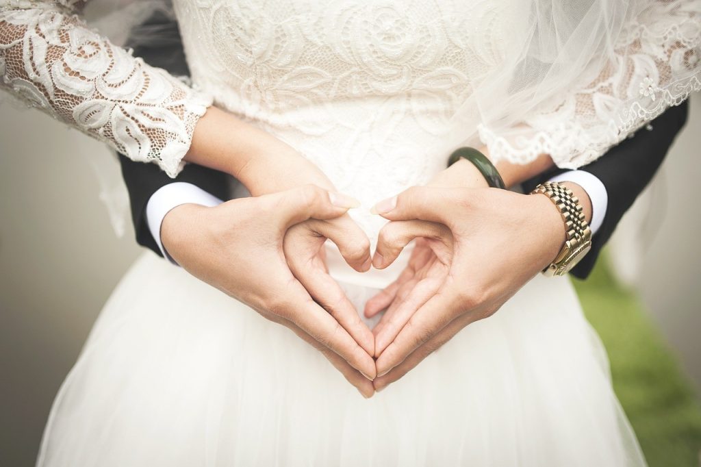 bride and groom forming heart with their hands