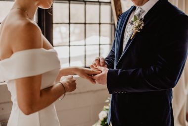 groom putting ring on bride