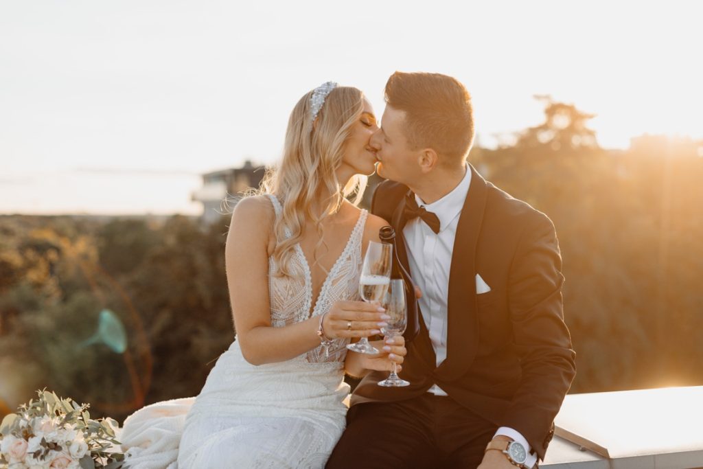 newlyweds kissing and clinking wine glasses