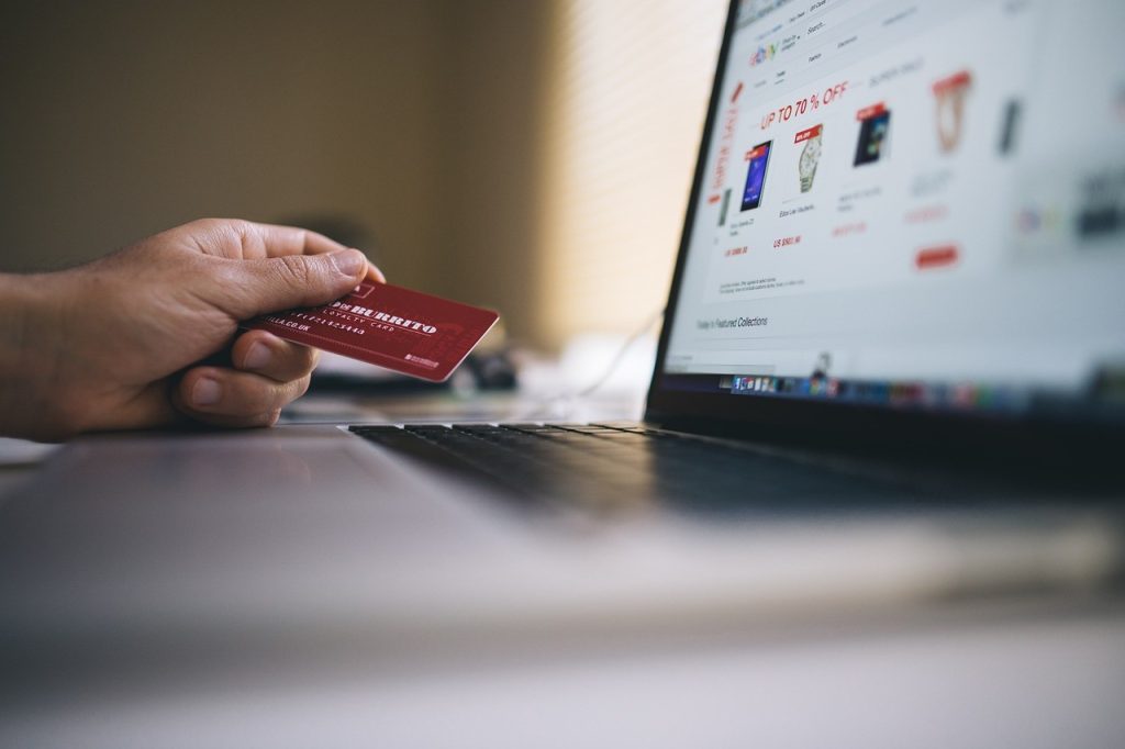 person holding a credit card in front of laptop